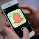 A person holding a mobile phone displaying the Snapchat app.